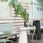 Dorik Cafe Table in a stylish outdoor café setting with a round tabletop and pedestal base